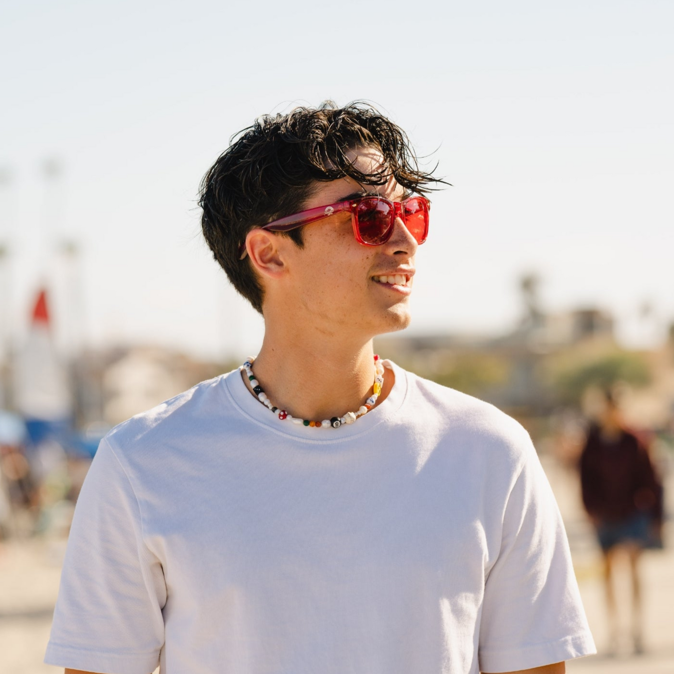 Person wearing red sunglasses and a white t-shirt with a blurred background